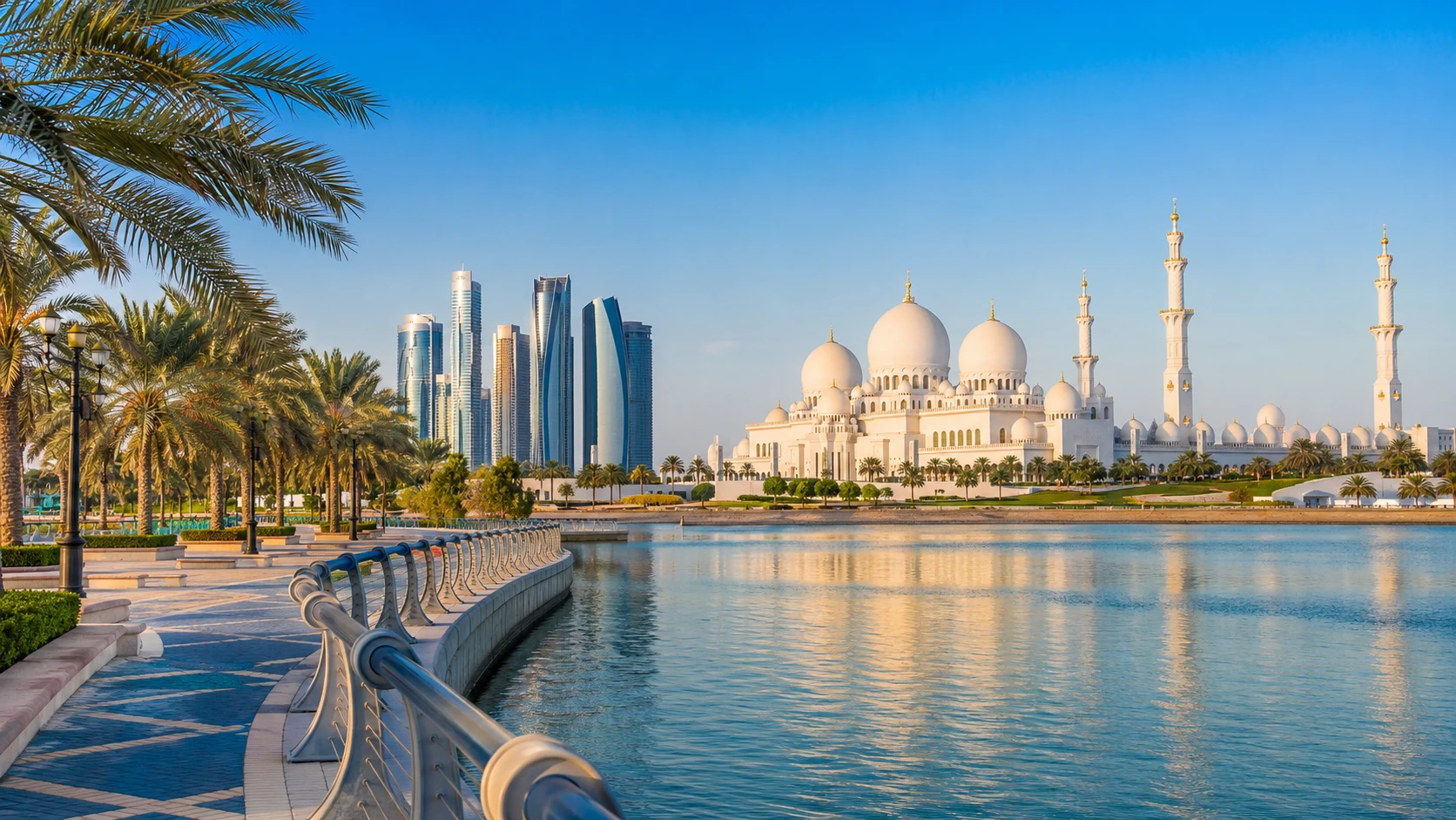 Sheikh Zayed Grand Mosque across the water with the Abu Dhabi skyline and a palm-lined corniche