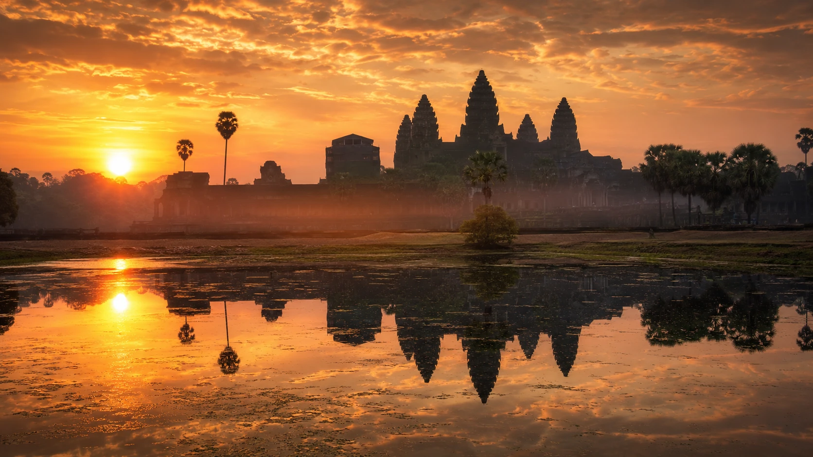 Sunrise over the temple towers of Angkor Wat reflected in the water