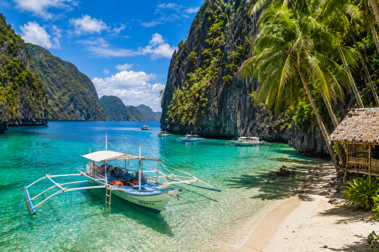 Outrigger boats in a turquoise lagoon below limestone cliffs, El Nido, Philippines