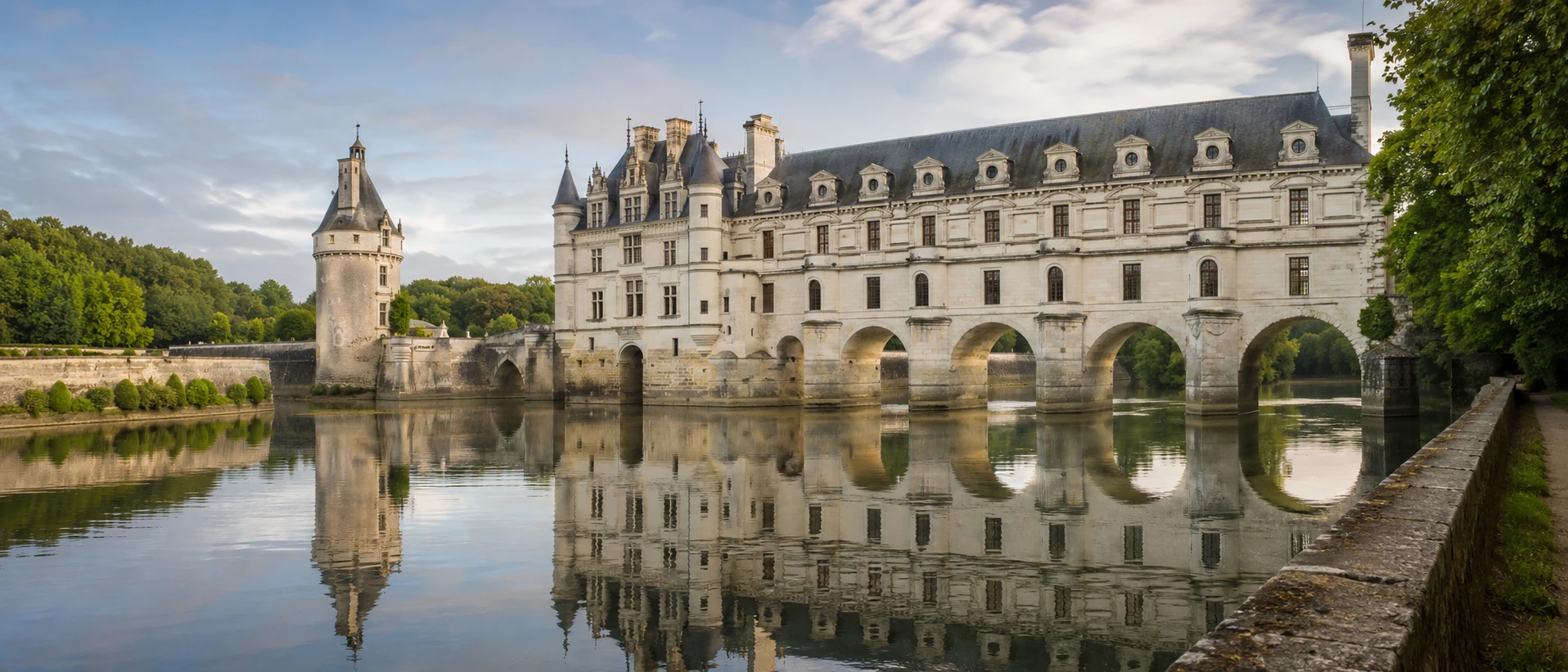 Château de Chenonceau spanning the River Cher at dawn, reflected in the still water