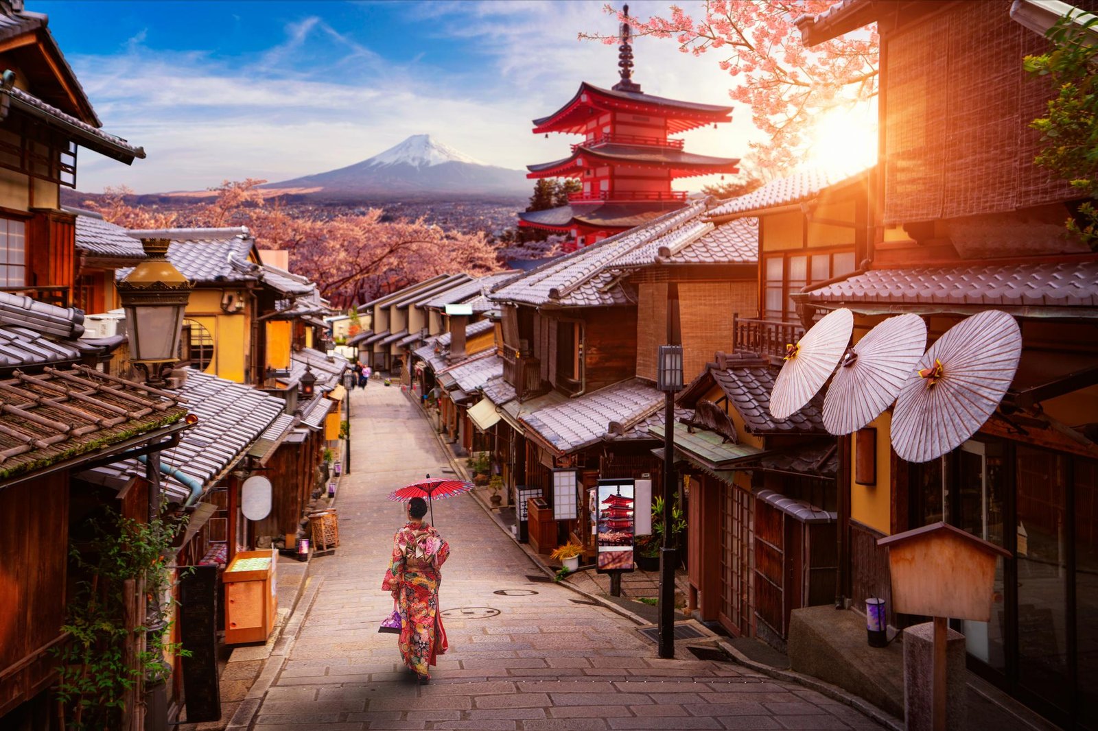 A woman in traditional kimono walking a historic Kyoto street toward Chureito Pagoda and Mount Fuji at sunset