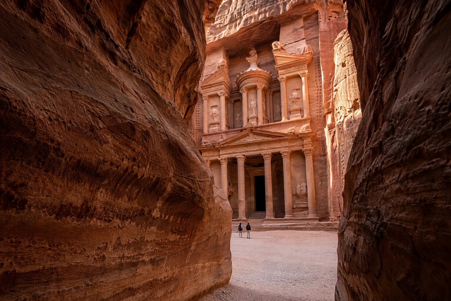 The rock-cut facade of Al-Khazneh, the Treasury, viewed through the narrow Siq canyon at Petra, Jordan
